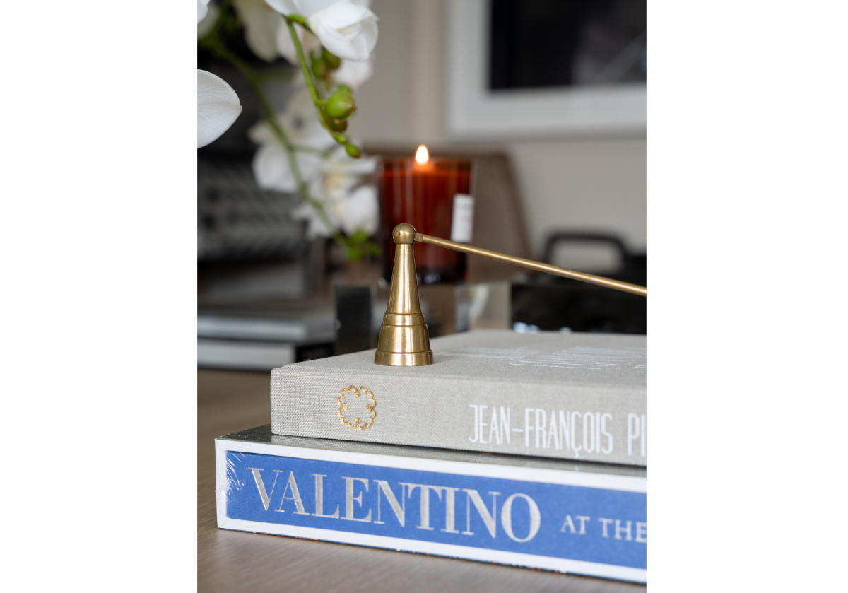 antique brass candle snuffer placed on a pile of books.