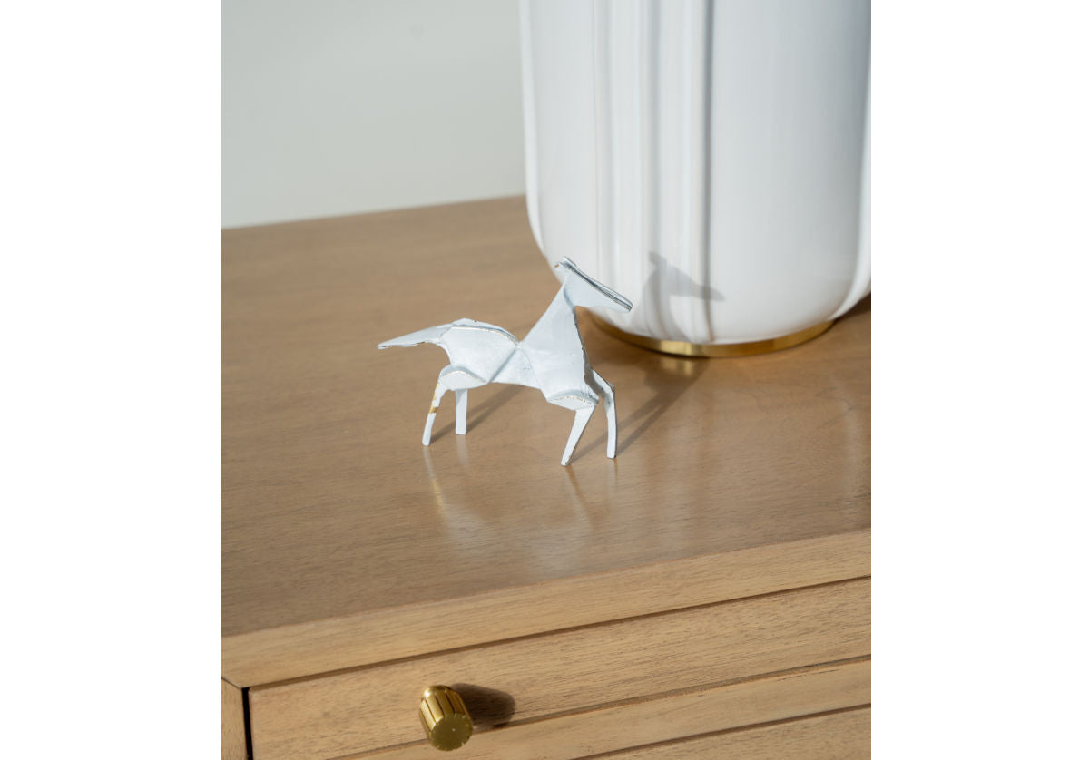 brass horse seen on a table next to a lamp.