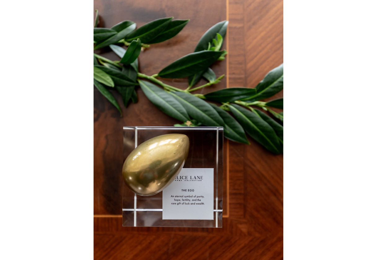 picture of a brass egg next to a branch a top a crystal cube.