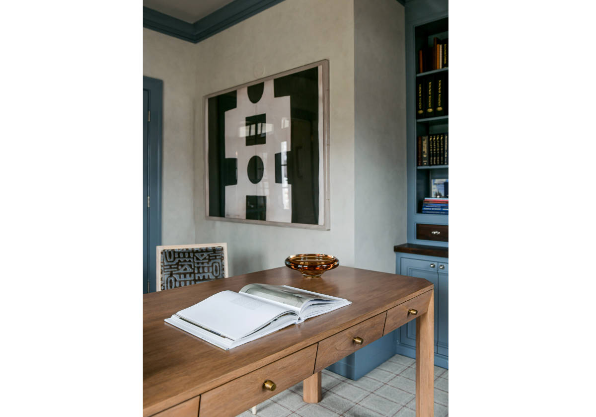 the brooklyn desk can be seen in the corner of the photo with a large book placed on top of it and a piece of art behind.