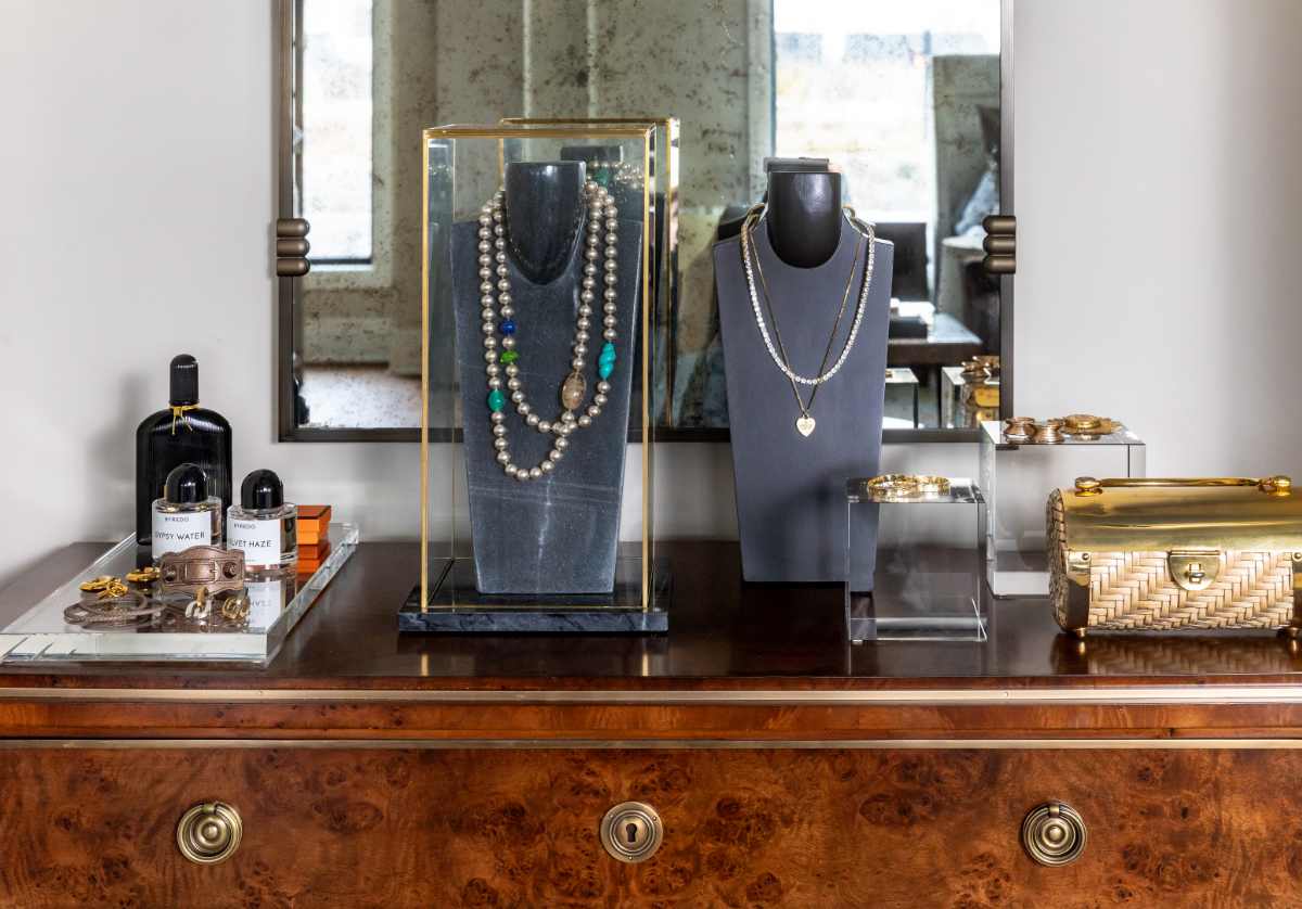 lifestyle photo of the crystal cube and slab ona. dresser. the crystal cube has earrings placed on it. while there is a glass display case with a darlene necklace display case inside of it.
