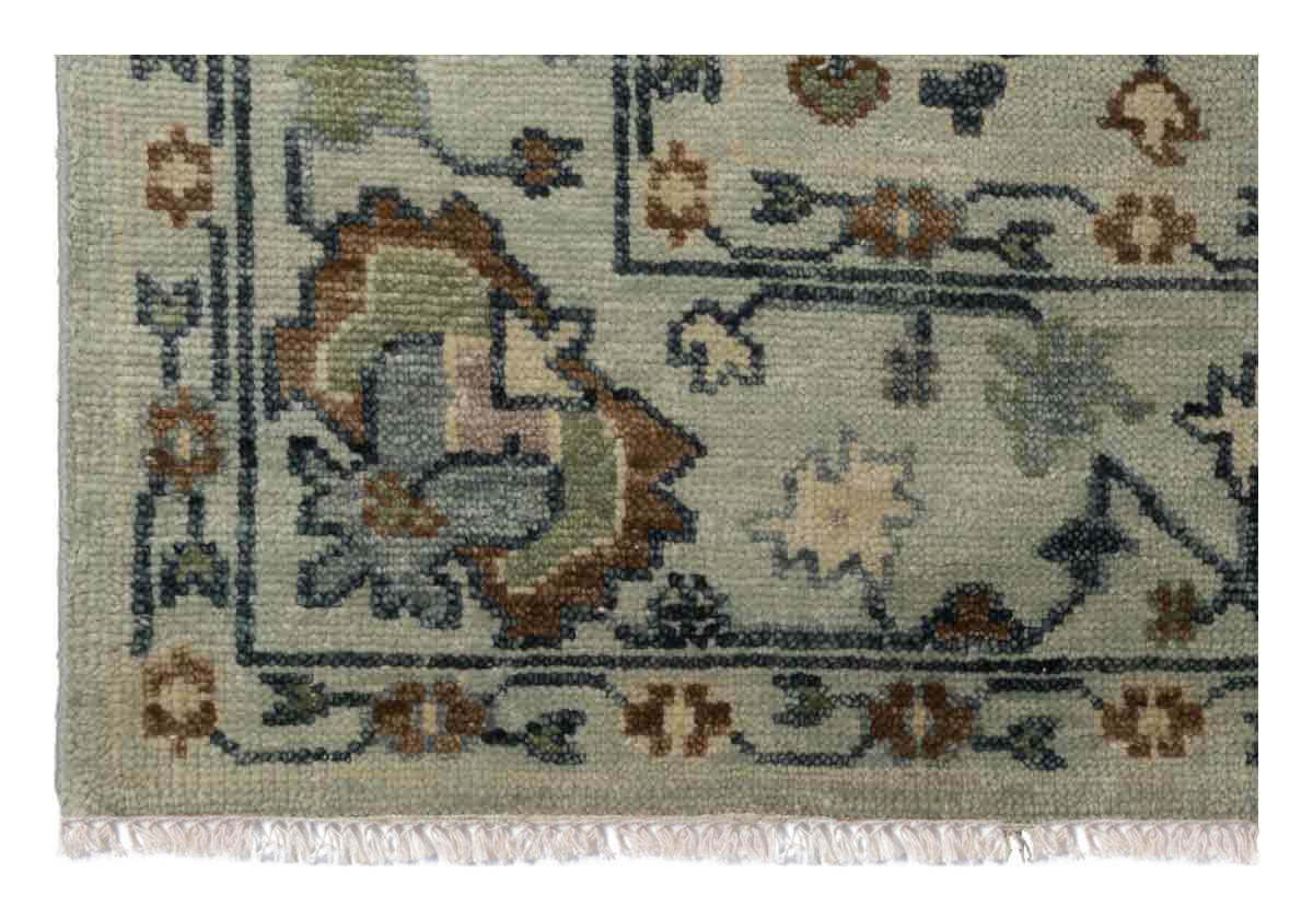 close up of the corner of the farrah rug, you can see delicate tassels on the ends and floral like designs through out the edges.