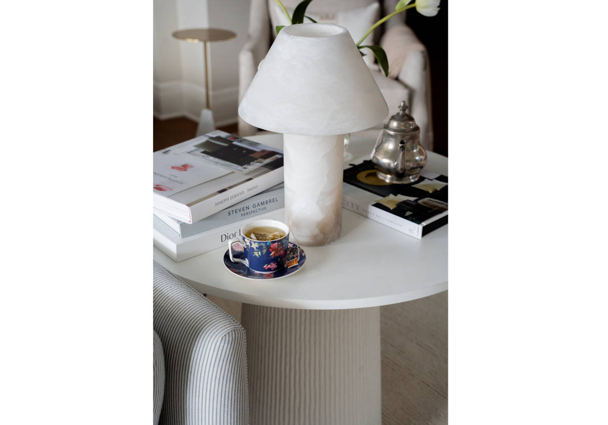 athena alabaster lamp seen on top of lucca side table and books.