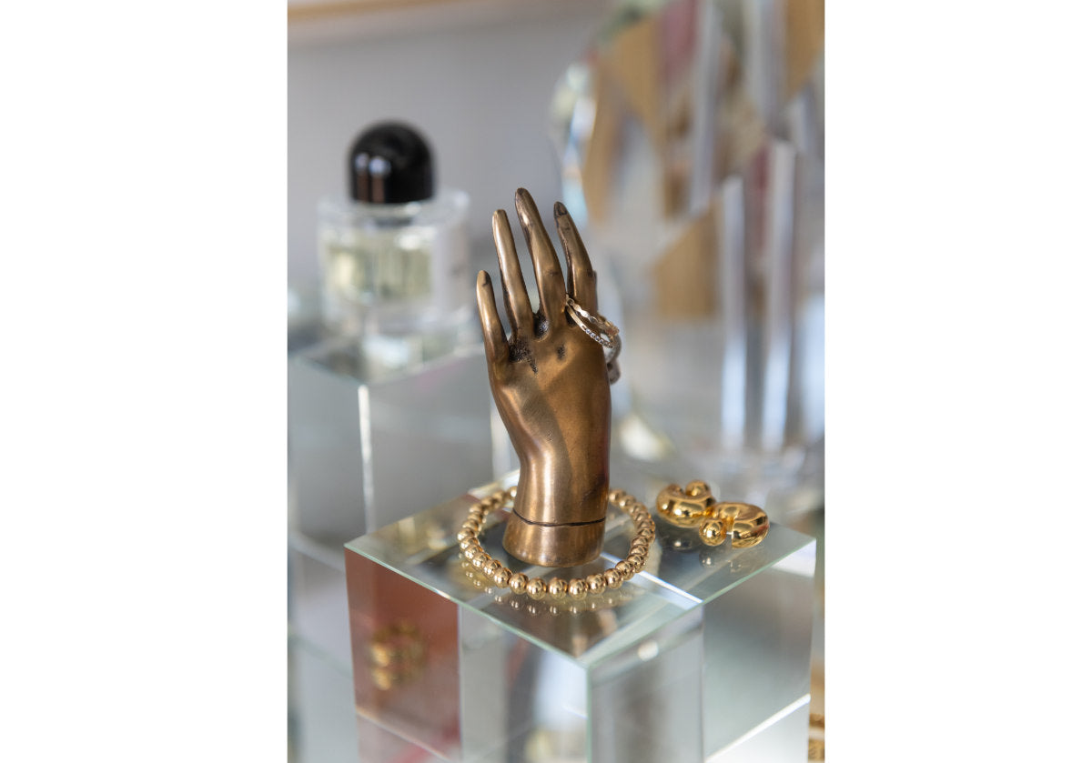 there is the bronze princess hand from alice lane on top of a crystal cube with jewelry on top of it.