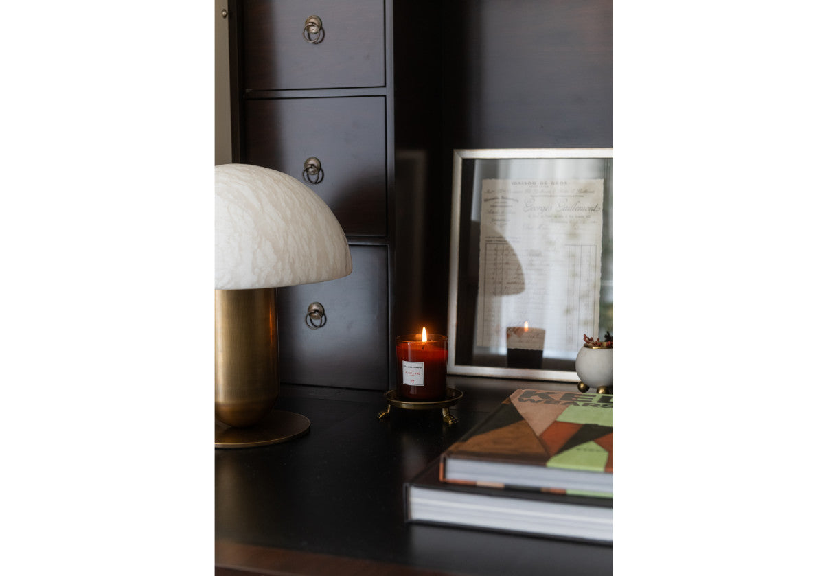 small clawfoot dish seen with a candle on a dresser with a lamp.