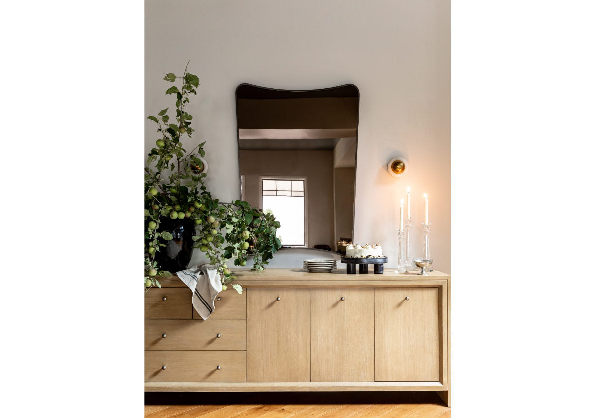 lifestyle photo of the ace sconce placed on the wall above some lit candles, next to a mirror.