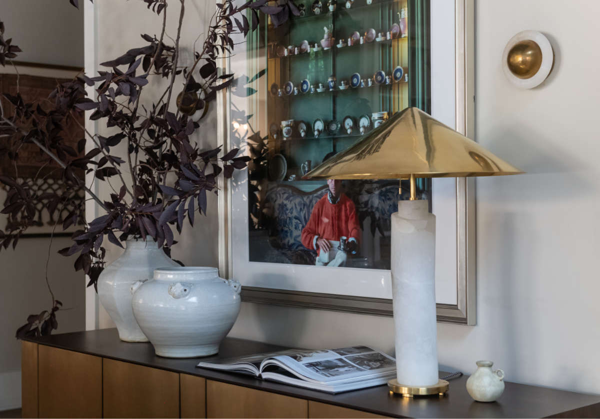 ace sconce being shown above a gold lamp and next to a picture.