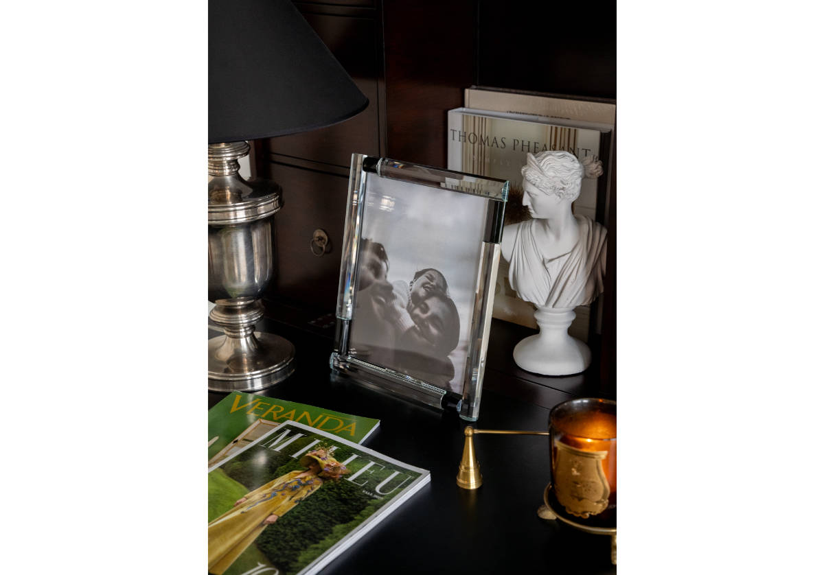 black and crystal frame placed next to a greek bust on a dresser.