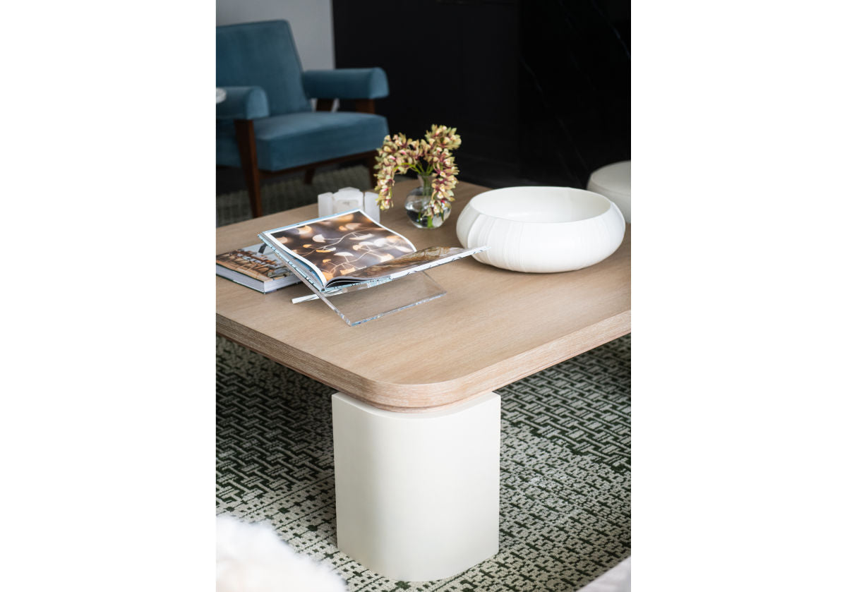 top down photo of the blair cocktail that makes a sculptural statement with its spacious white oak top elevated by four radius legs. The natural wood graining and patterning provide a beautiful contrast to its smooth, creamy base for an elevated design. with a marble bowl and the lucite book display on top.
