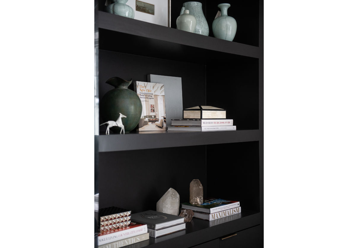 lifestyle photo of the brass horse on black shelving with decor and other books.