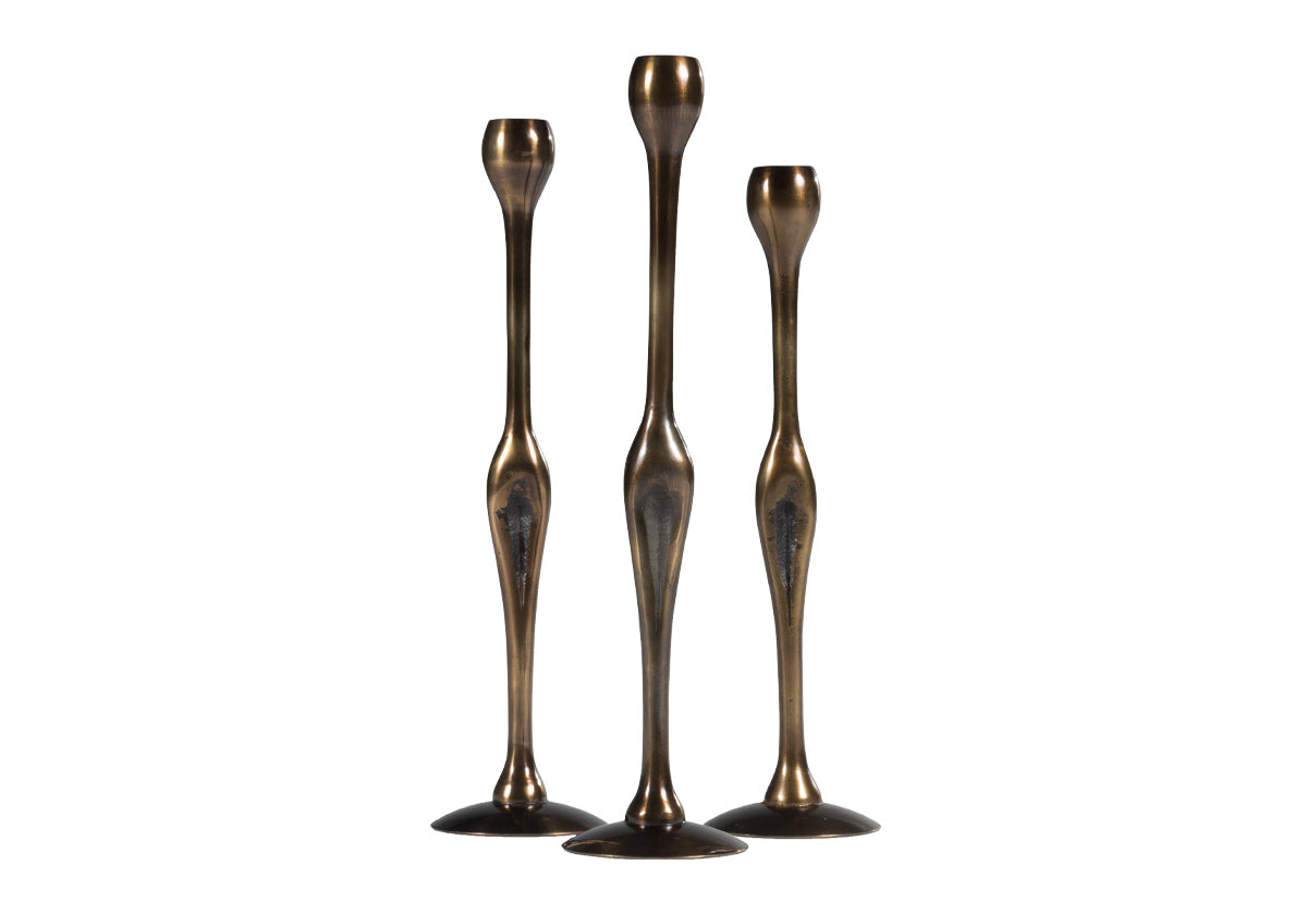 Foxy and dimensional, the Figure Brass Candlestick gives a sultry, 70's chic vibe. Its intriguing shape and rich bronze finish create a striking addition, styling well on mantles, center hall tables, and cocktail tables. Style a matching pair or mix and match the heights for an additional layer of interest.