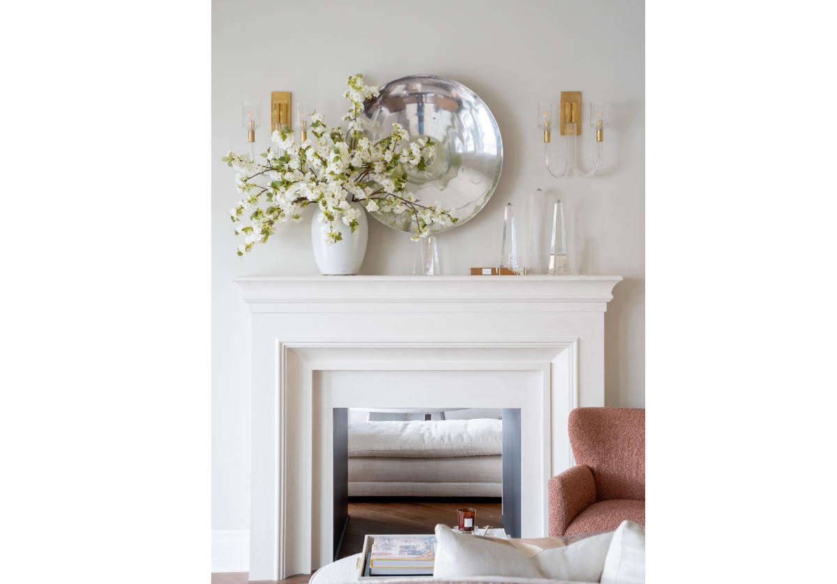 white vase on the left of a fireplace mantle with different sized crystal obelisks.