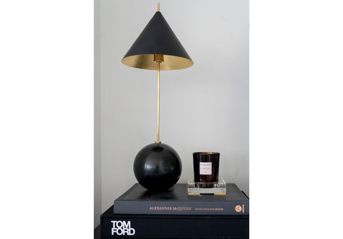 gold and white crystal candle dish can be seen on some books and next to a black ball lamp.
