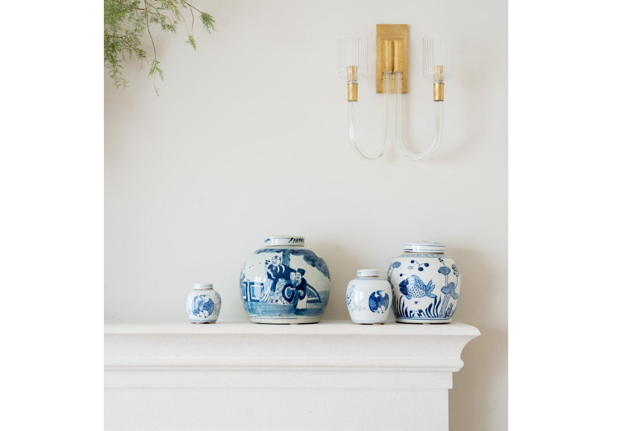 lifestyle photo of the small crane jar ona. fireplace mantle with a sconce above it.