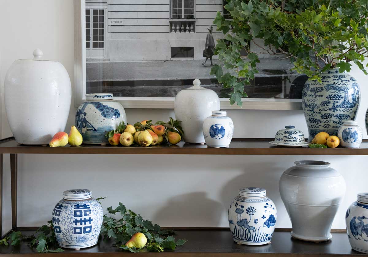 two wood shelves adorned in leaves and blue and white jars. the double happiness jar is in the bottom left corner by itself.