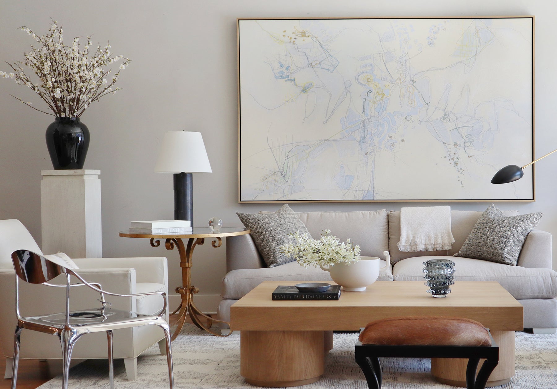a photo of a large black vase on a pedestal in a living room. with a coffee table and sofa in the center of the room.