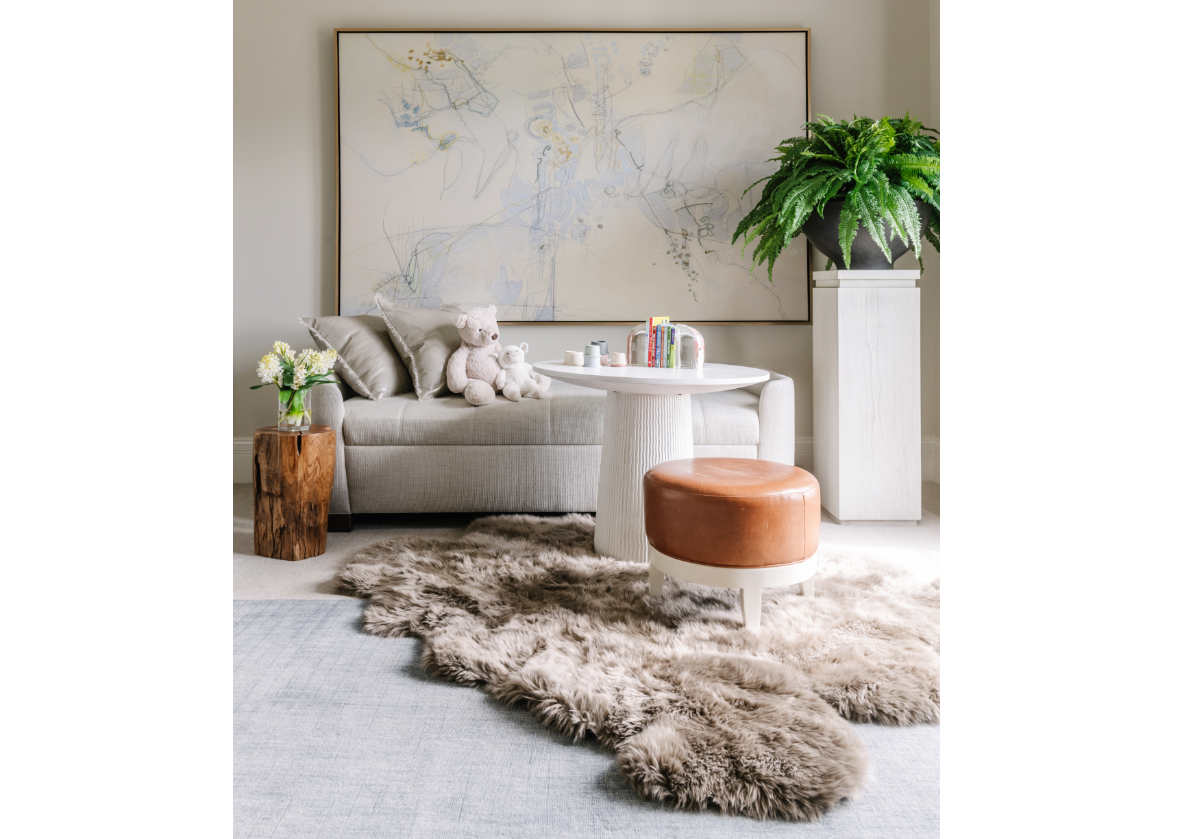 crystal bookends are seen on the lucca table next to a pedestal and sofa with a stuffed bear on it.