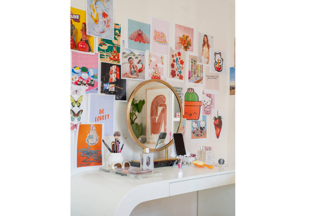 lifestyle picture of brass alice vanity mirror surrounded by cut out pictures on the wall. 