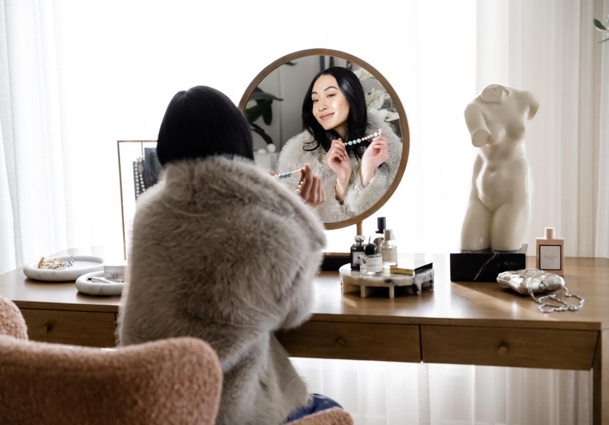 model looking in the alice vanity mirror, while wearing a necklace. 