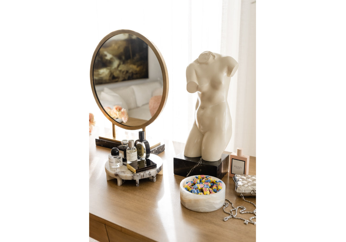 lifestyle photo of brass alice mirror next to venus statue 