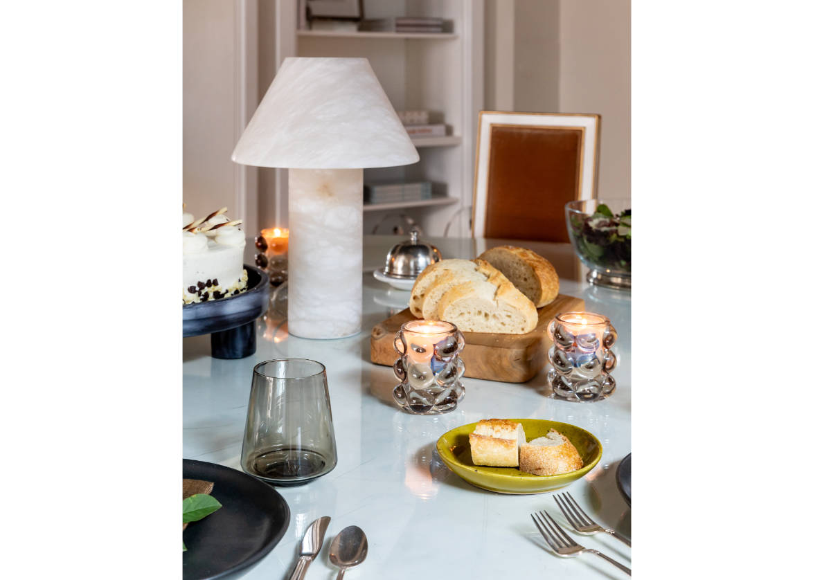 lifestyle photo of athena alabaster lamp on top of dining table, adorned with dinnerware. 