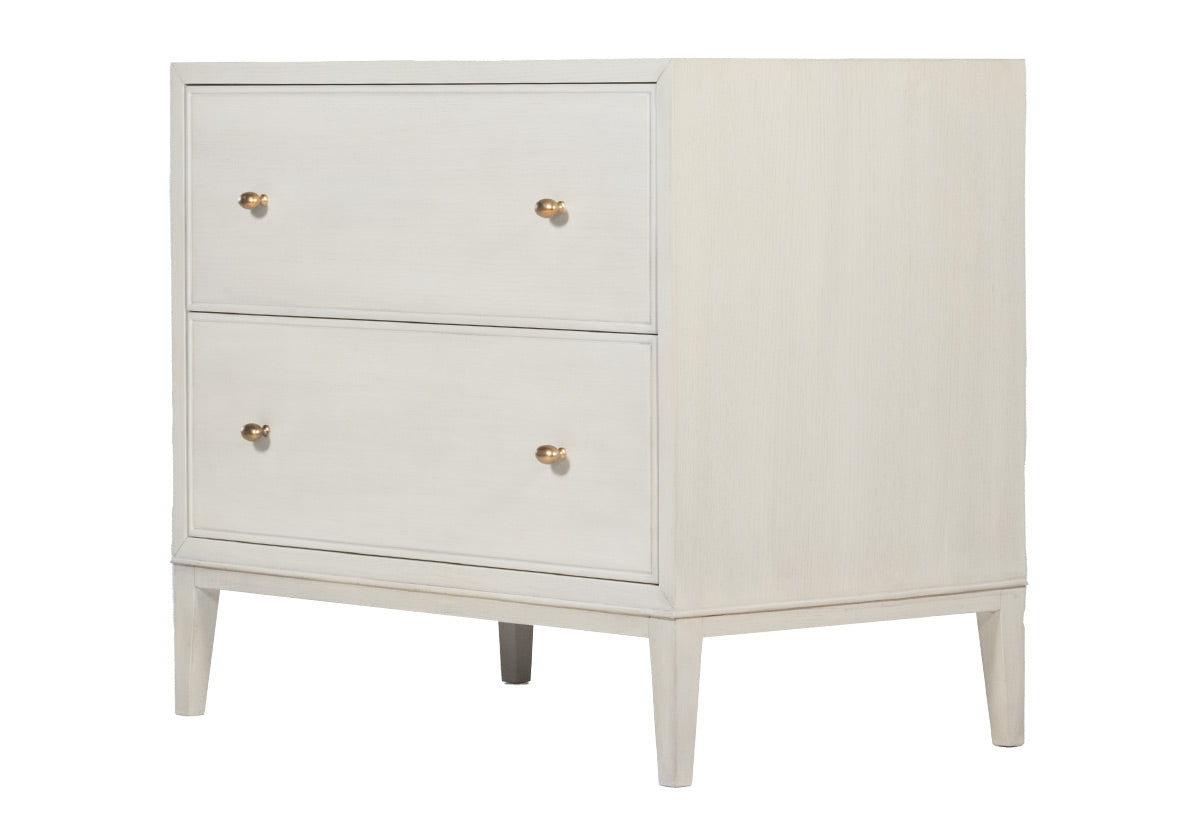 sideways view of the ava white nightstand. facing the left of the screen. you can see its bright gold knobs on the front the dresser doors. 