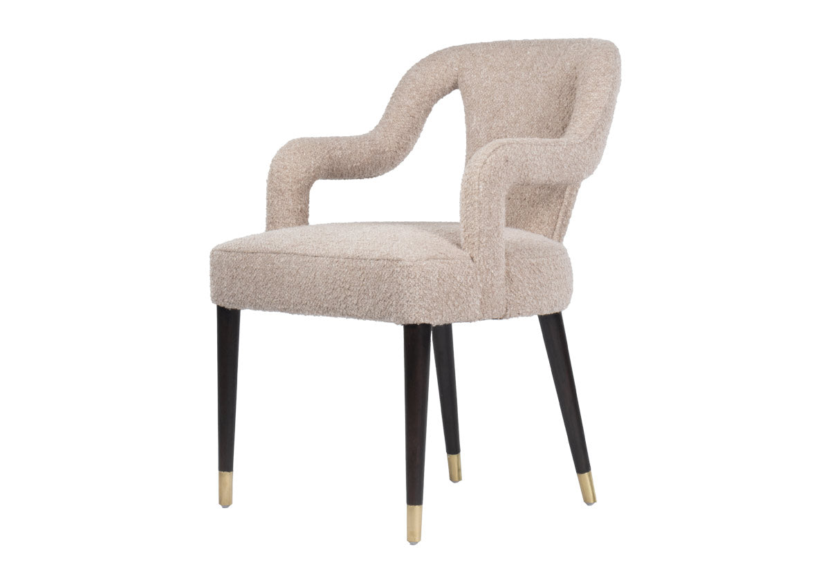 The Bobbie showcases a shapely form with its sloping back, curved arms, and canted legs. Covered in the industries finest Libeco fabric, created in Belgium, its Berber Linen upholstery in a versatile neutral elevates a sophisticated style. Brass-capped feet beautifully contrast its walnut-finished legs for a luxurious, tasteful design.