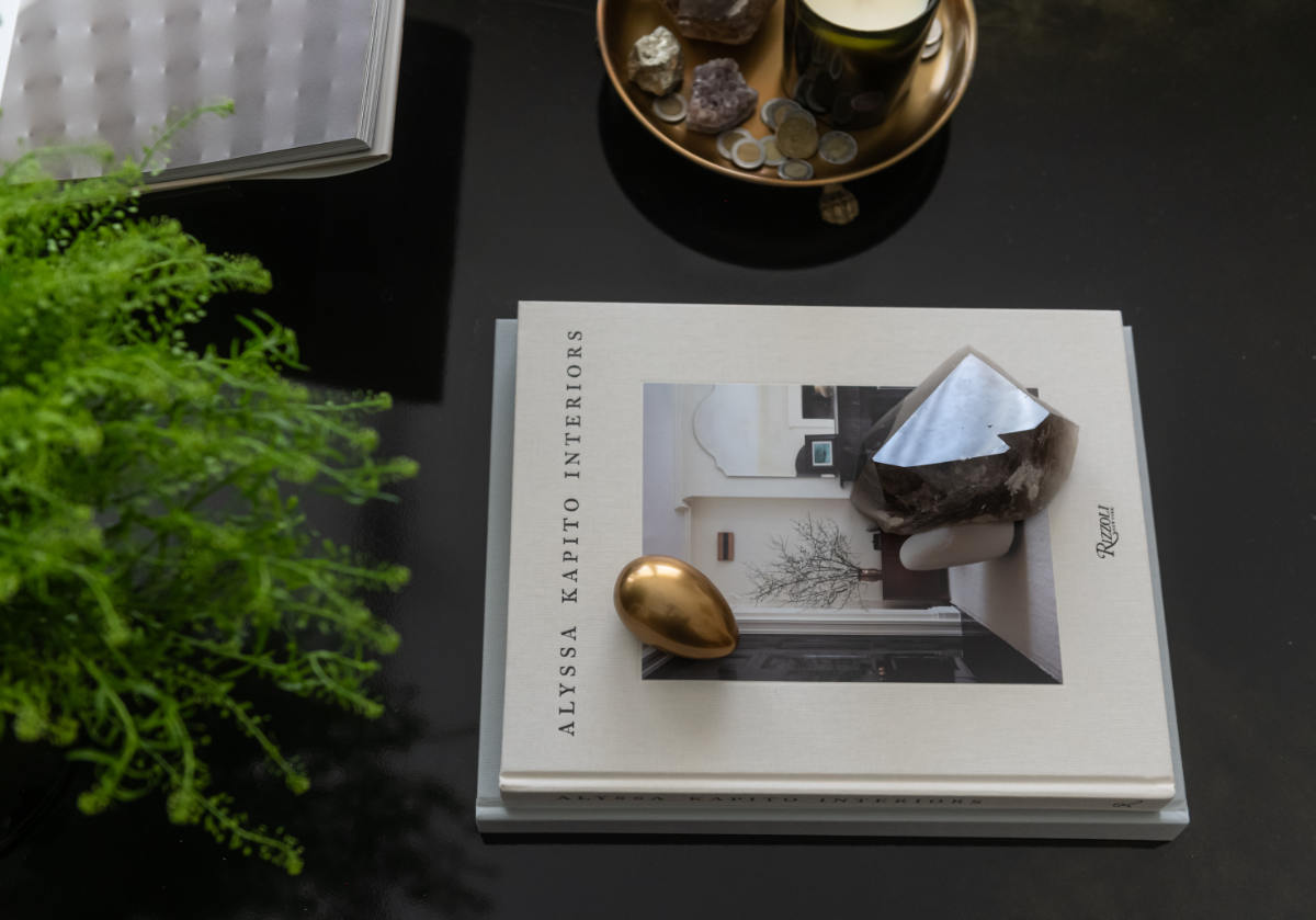 picture of the brass clawfoot tray holding some treasures. with a pile of books and a gold egg with a crystal next to it. 