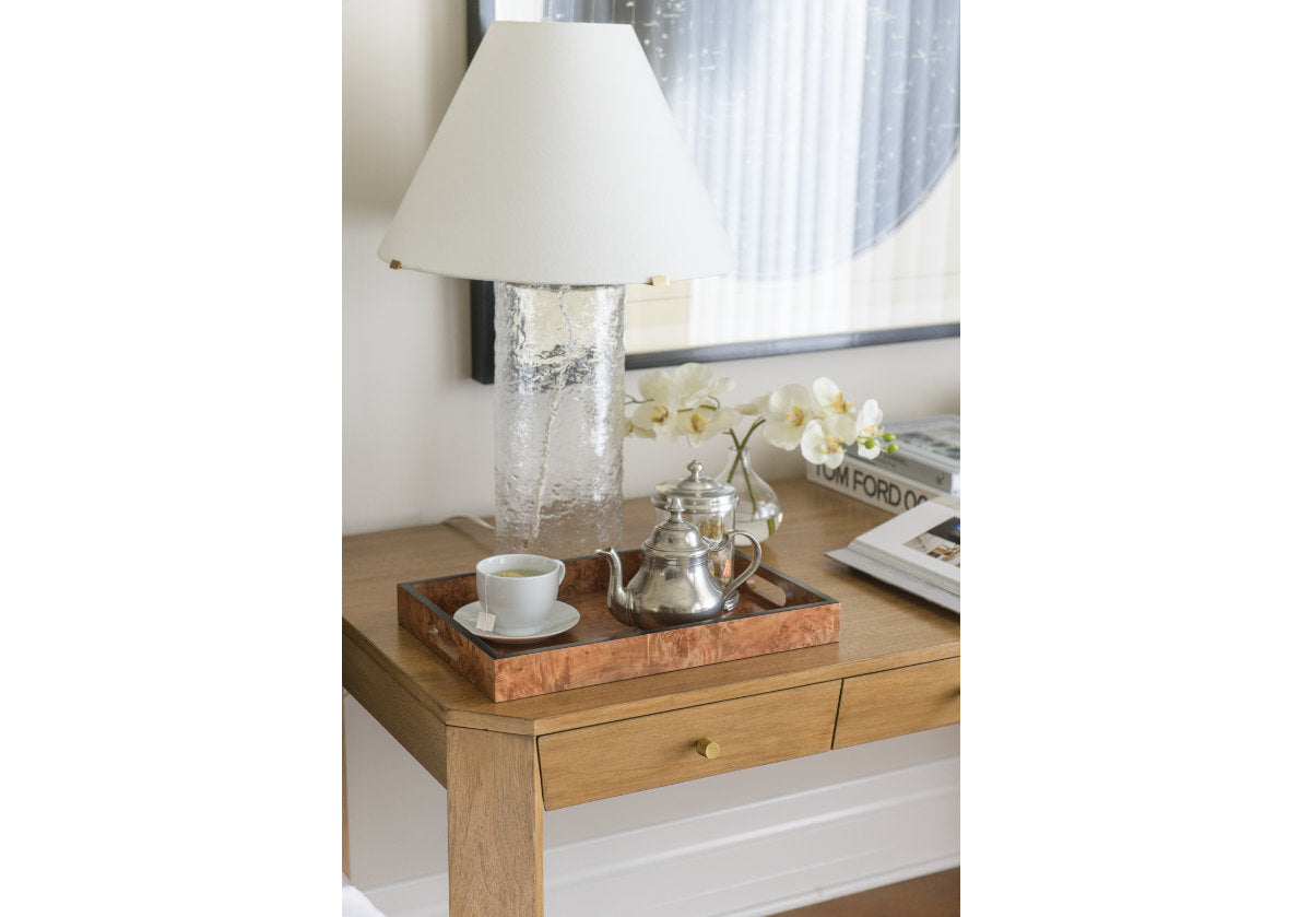 brooklyn desk is featured in the center of this photo. with a burled wood box, silver tea pot, and tea cup are placed on top with a desk lamp. 