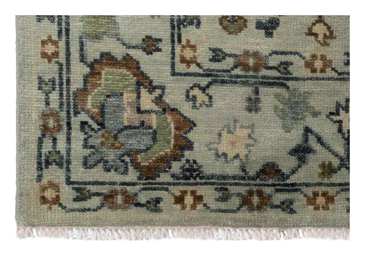 close up of the corner of the farrah rug, you can see delicate tassels on the ends and floral like designs through out the edges. 