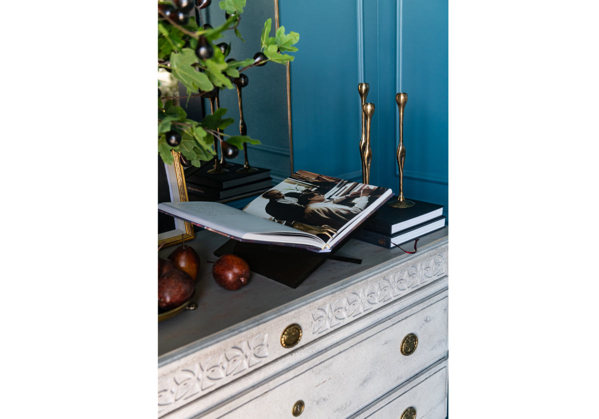 the chocolate book display can be seen on a white dresser with the figure brass candlesticks. 