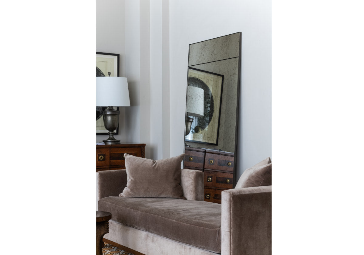 the leo sette is sitting in front of the eden floor mirror in a living room. 