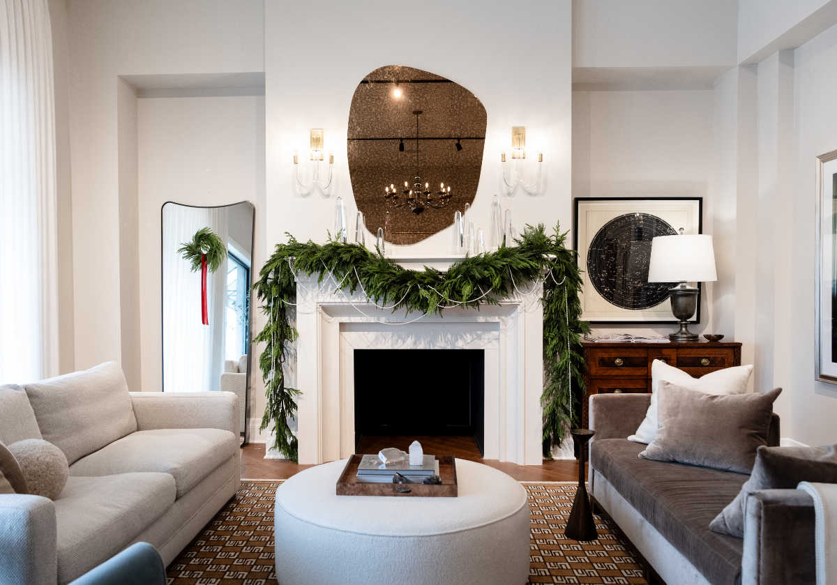 Multiple different sized obelisks can be seen on a fireplace mantle with a pearl and pine garland.