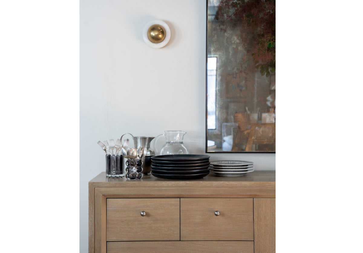 lifestyle photo of the ace sconce shown above a cabinet with dinnerware. 