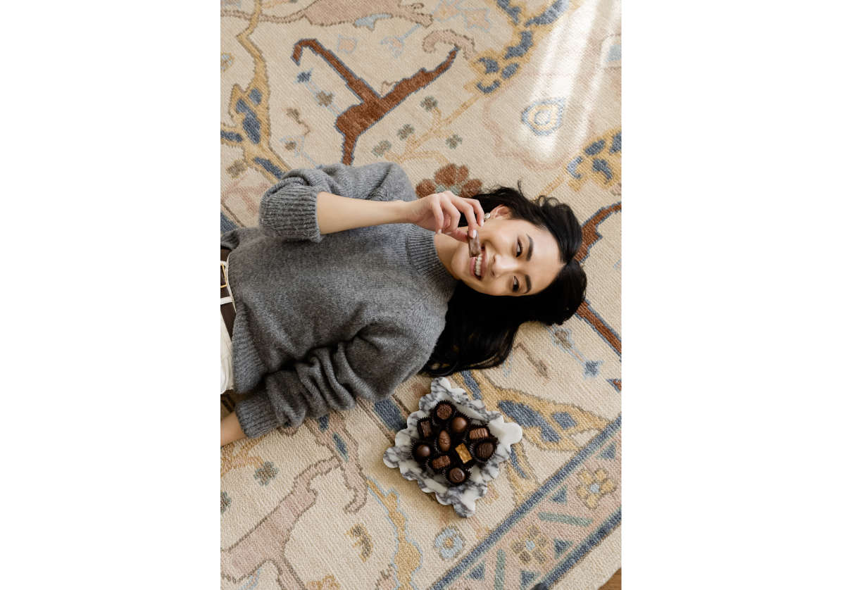 amoure tray placed on carpet next to model eating chocolate. Amore tray is made out of calacatta viola marble. 