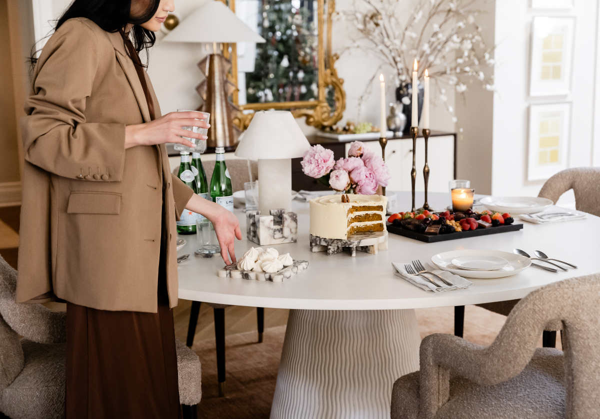 lifestyle photo of model standing next to coffee table with amore marble tray and other marble products from alice lane. 