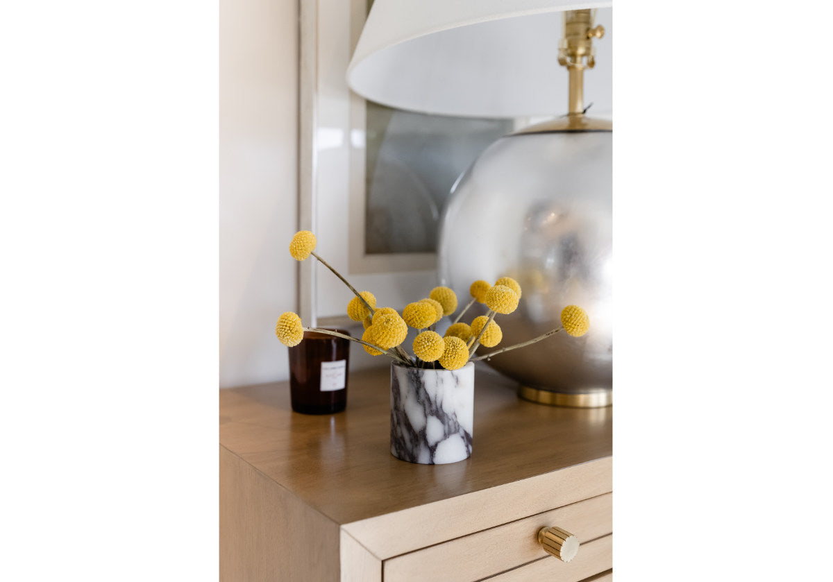 picture of calacatta viola marble canister with blooms inside of it, placed on a dresser. 