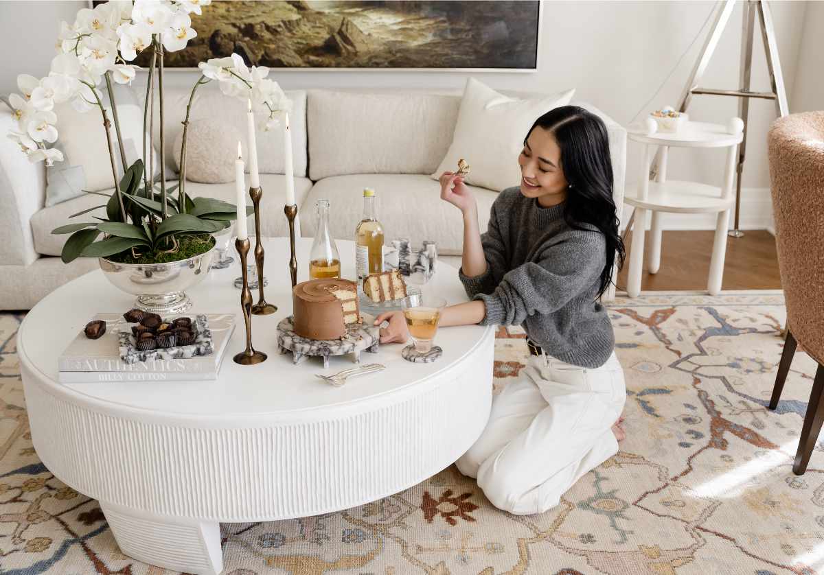 lifestyle photo of model sitting at coffee table, with amore marble tray sitting on a stack of books. 