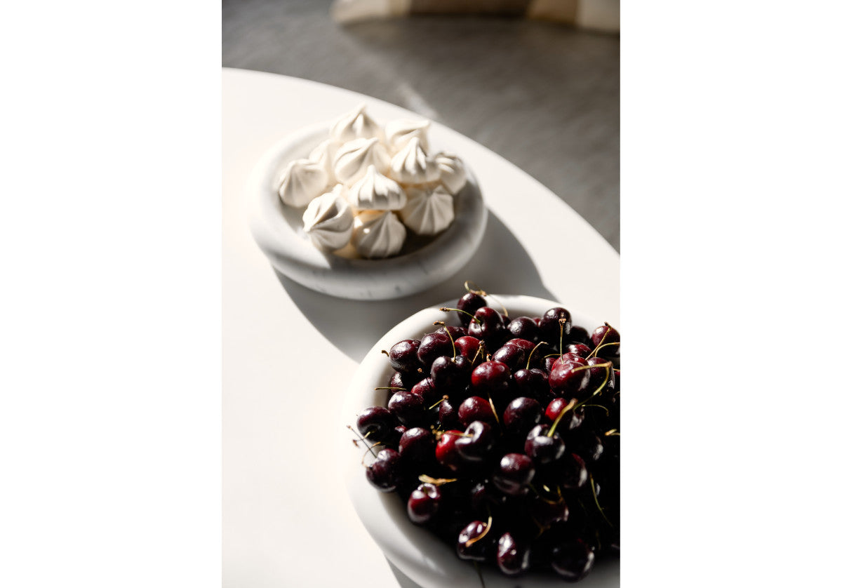 small and large milan dishes shown in lifestyle picture. the small dish has cookies on top and the large dish has cherries on top. 