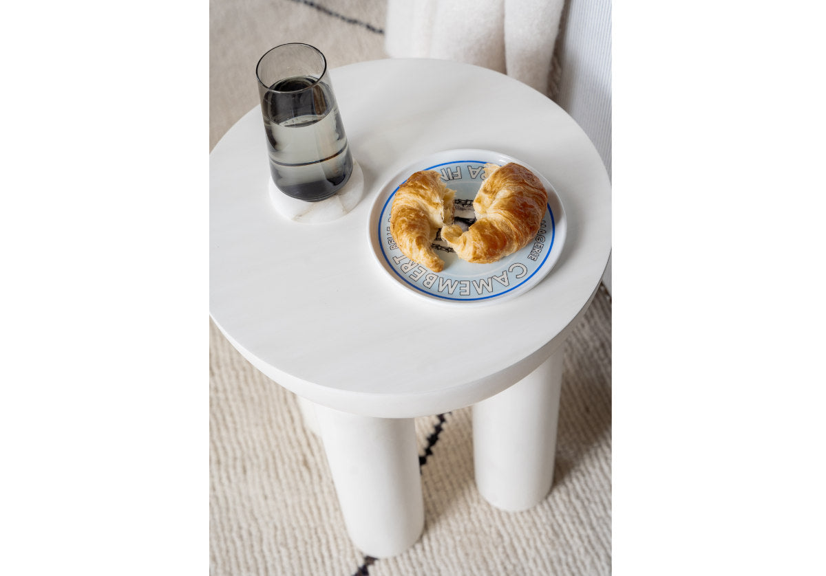 small white anders table with croissant and water on top. 