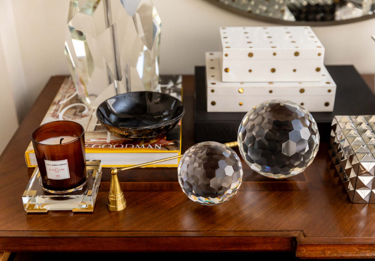 two different sized crystal orbs ona. dresser with a crystal and gold candle diffuser and decorative boxes. 