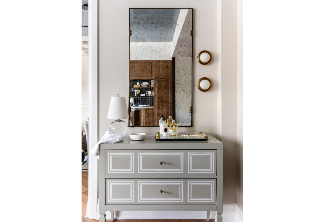 arlo mirror shown above a cabinet and next to some sconces. 