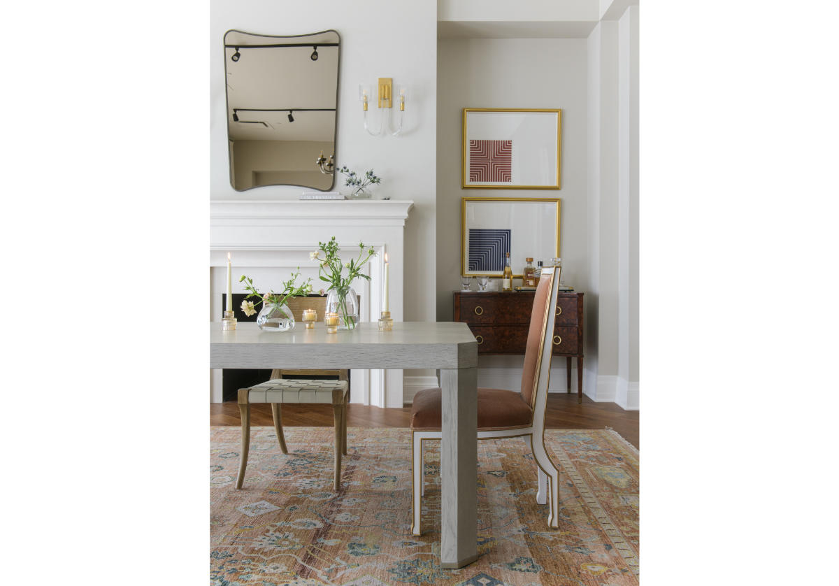 the end of the arthur table can be seen with the felix chair on the end of it with the iris mirror in the background above a fireplace mantle. 