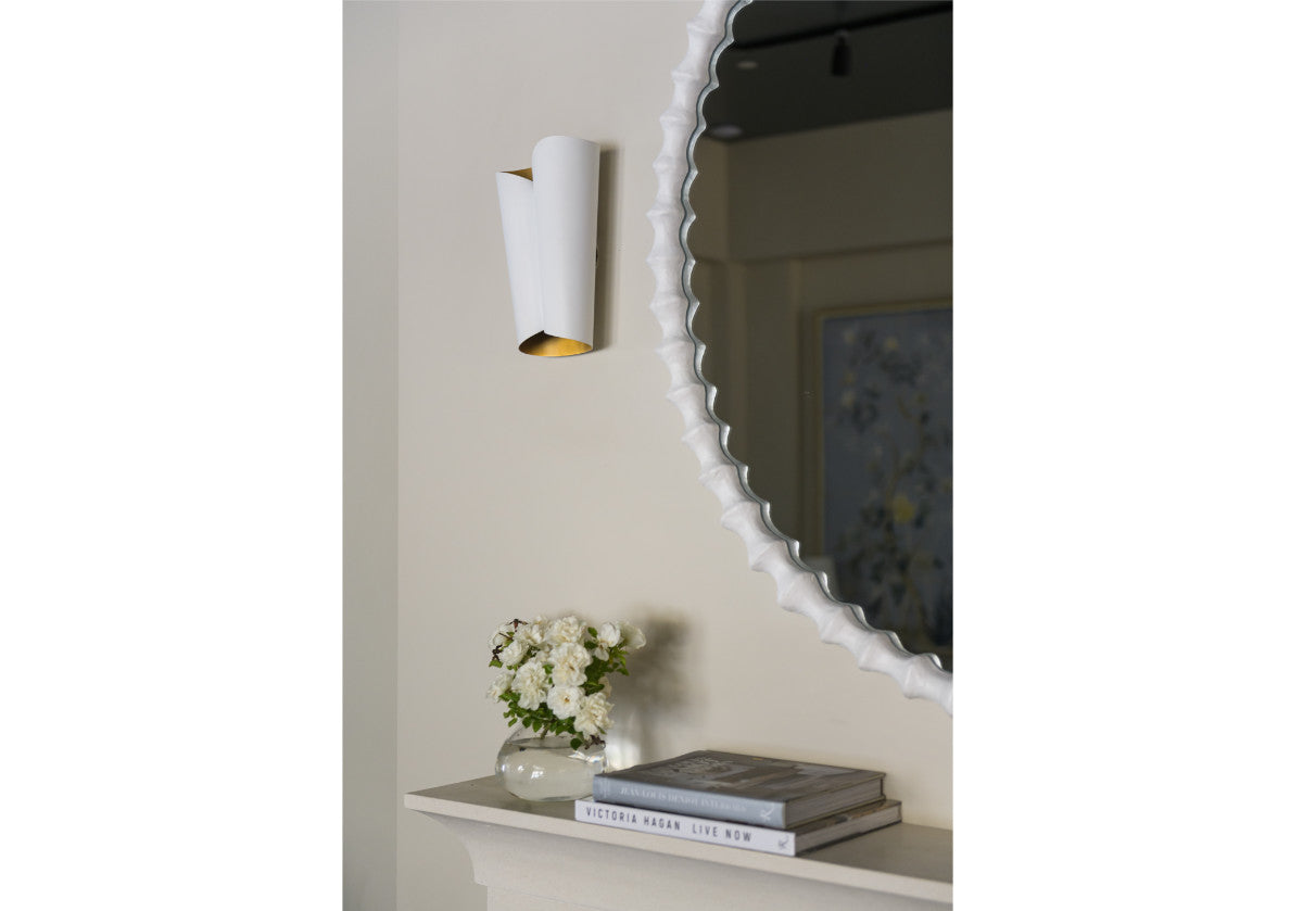 lifestyle photo of astrid sconce next to a mirror from alice lane. 