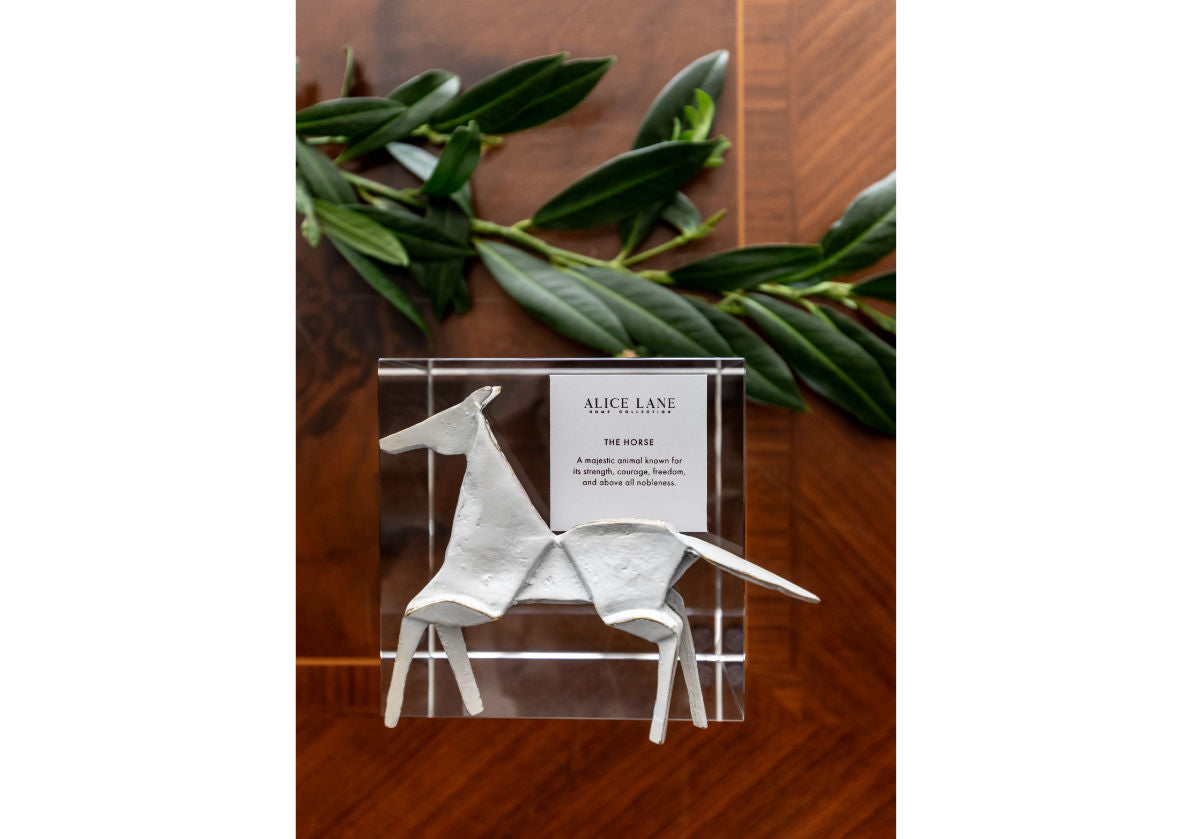 lifestyle photo of the brass horse sitting on top of a crystal cube. 