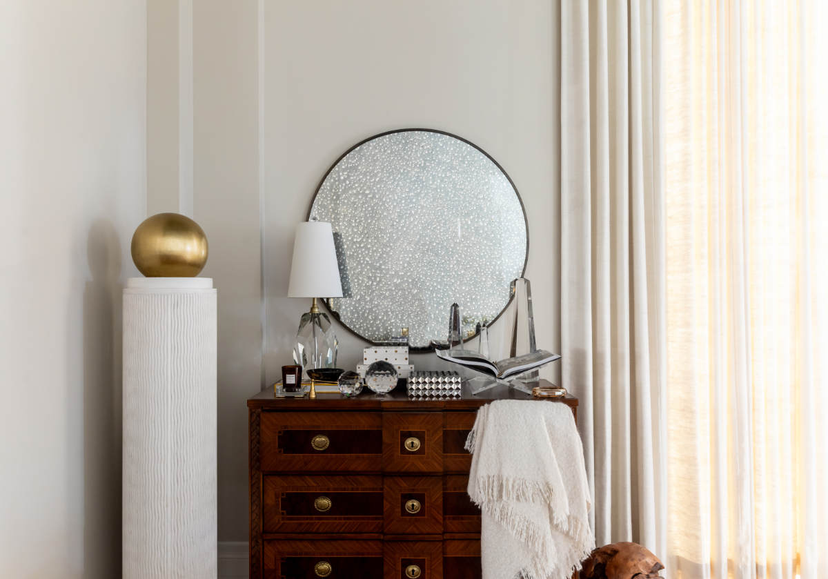 under the caspian mirror is a crystal lamp, crystal candle diffuser, crystal orb, decorative boxes all sitting on top of a dresser from alice lane. 