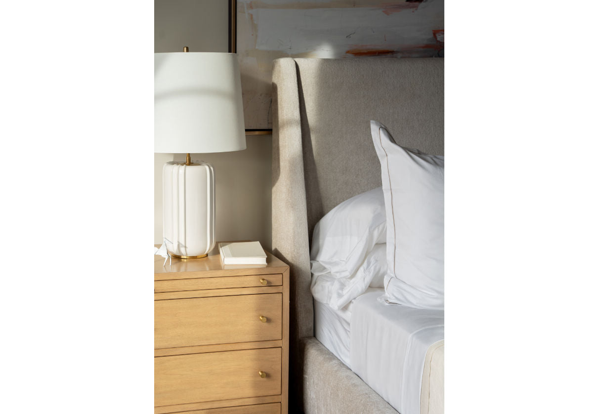 lifestyle photo of the charlie bed next to a dresser with a lamp on it. 