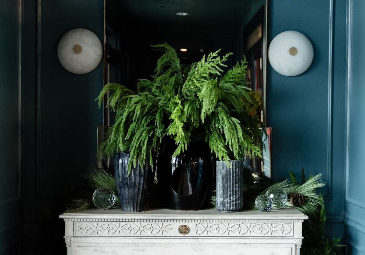 pine stems inside marble vases on a white dresser with crystal orbs. 