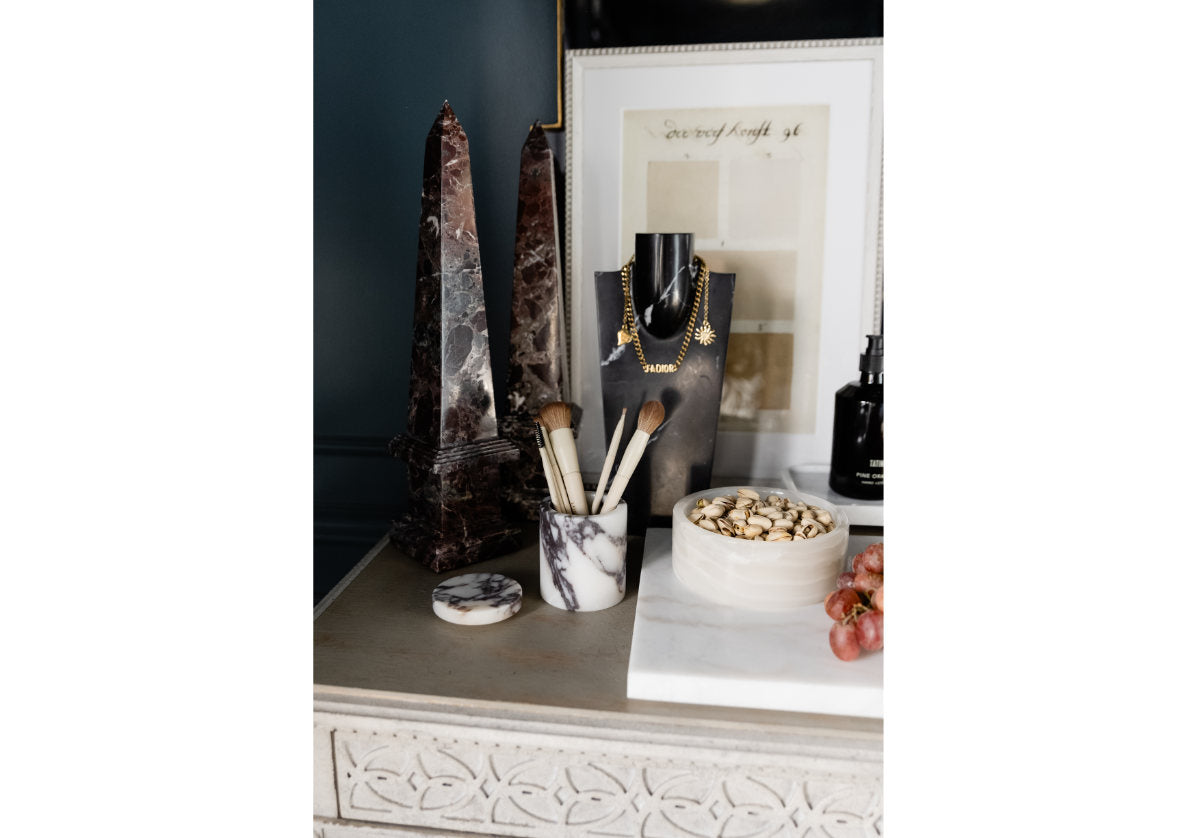 darlene necklace display of a white dresser with two marble obelisks and a marble makeup brush holder. 