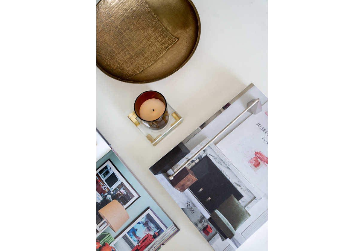 top down photo of the crystal and gold candle diffuser with a candle inside of to next to a gold bowl and some books. 